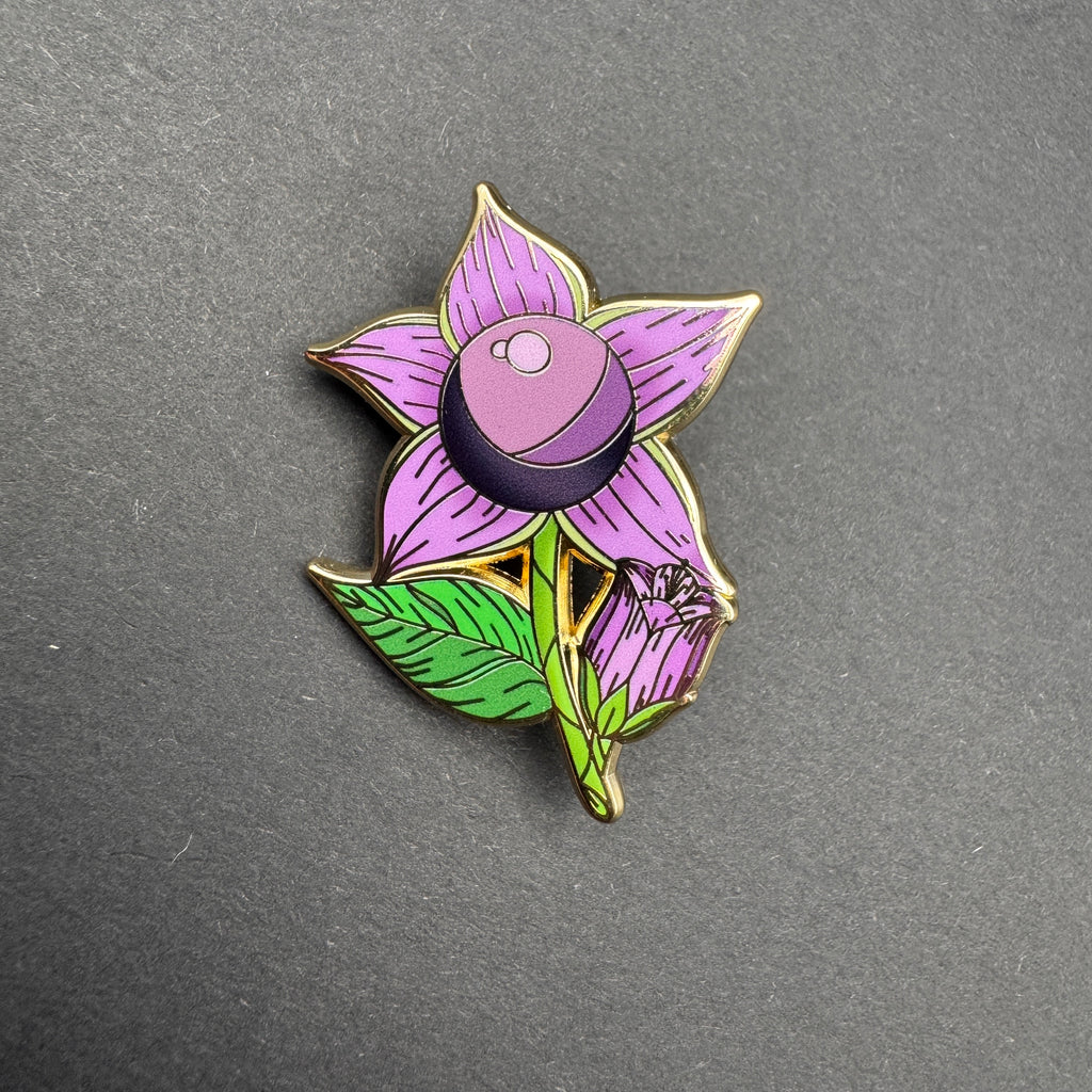 Floral-themed pin with purple flower and green leaves on a gray background