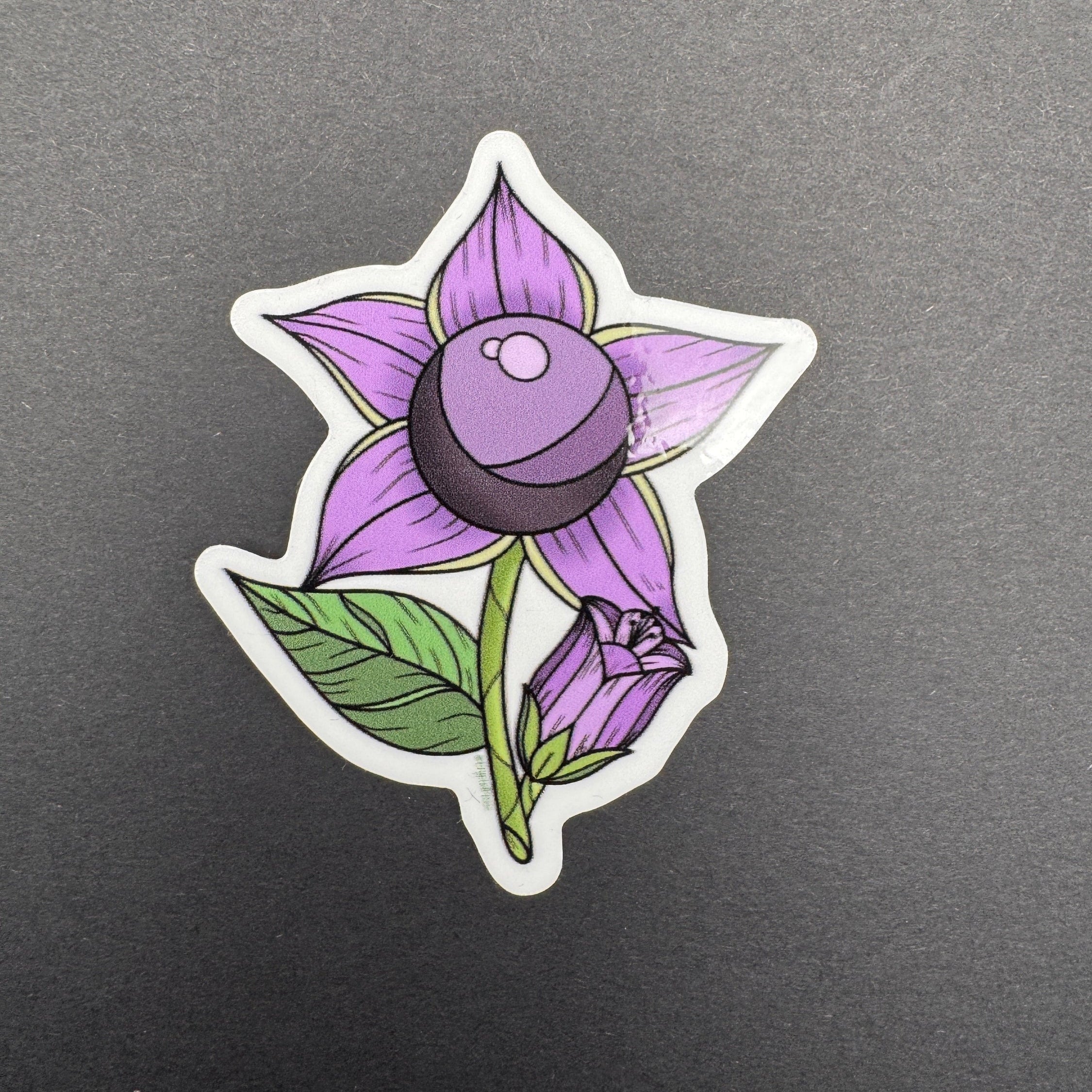 Sticker of a purple flower with green leaves on a gray background