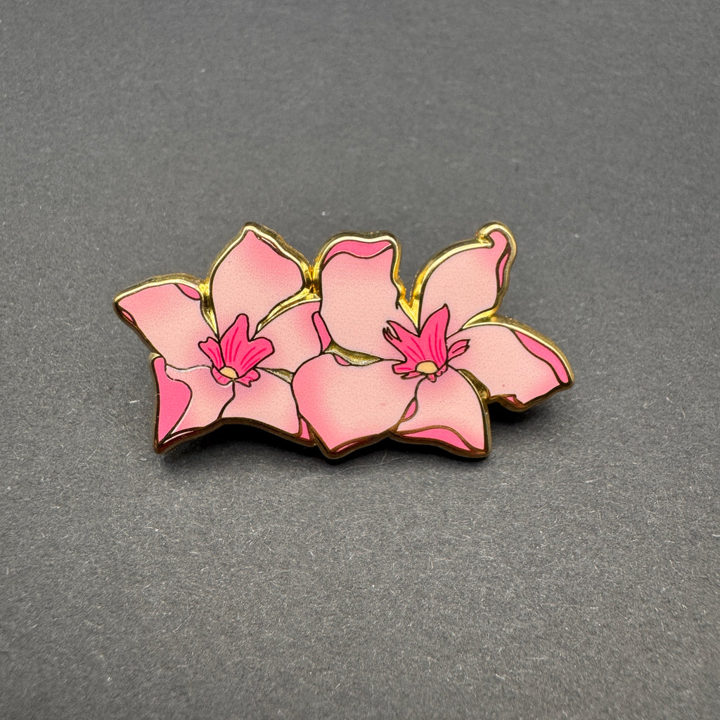 Pink orchid-shaped pin on a gray background
